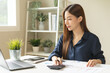 © KMPZZZ - Account finance, asian young business woman hand use calculator for calculate budget, cost and income of company from charts, reports paperwork, plan spend money expenses, working on desk at home.