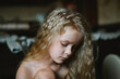 close-up portrait of a pensive, sad little girl with long curly hair at home