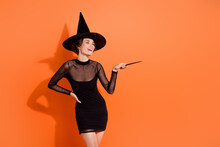Photo Of Pretty Young Girl Point Magic Wand Harry Potter Character Wear Stylish Black Halloween Witch Garment Isolated On Orange Background