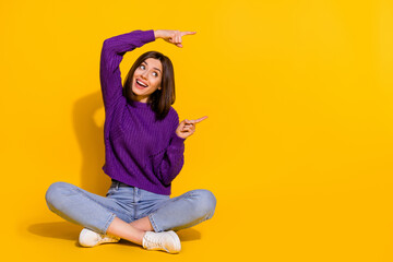 Wall Mural - full body photo of cheerful pretty lady sit floor look direct fingers empty space isolated on yellow