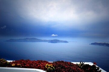 Wall Mural - Mist on the Santorini Island, Greece. View of the Mediterranean Sea in the morning haze. Filmed during a trip to the Mediterranean and the Cycladic Archipelago. From the shore. Among the flowers. 