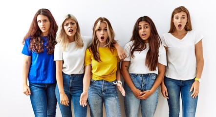 Poster - Group of young girl friends standing together over isolated background in shock face, looking skeptical and sarcastic, surprised with open mouth