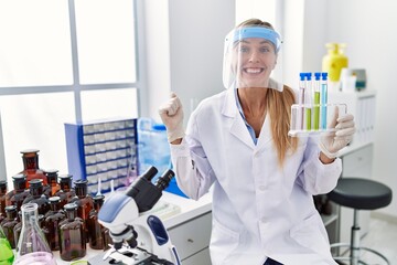 Poster - Beautiful woman working at scientist laboratory screaming proud, celebrating victory and success very excited with raised arm