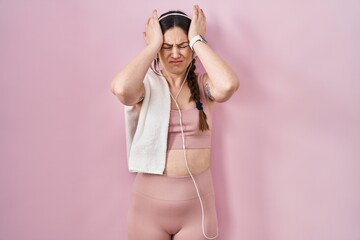 Poster - Young brunette woman wearing sportswear and headphones suffering from headache desperate and stressed because pain and migraine. hands on head.