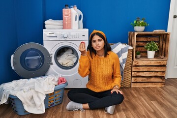 Poster - Young hispanic woman doing laundry doing italian gesture with hand and fingers confident expression