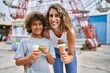 Mother and son smiling confident eating ice cream at theme park