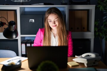 Canvas Print - Young caucasian woman working at the office at night winking looking at the camera with sexy expression, cheerful and happy face.