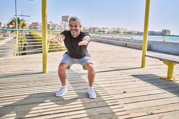 Poster - Middle age hispanic man wearing sportswear training at seaside