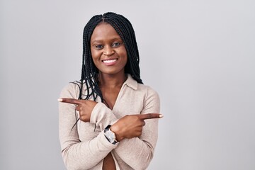 Sticker - African woman with braids standing over white background pointing to both sides with fingers, different direction disagree