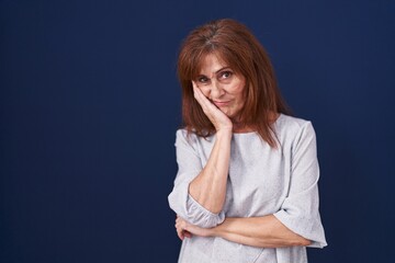 Sticker - Middle age woman standing over blue background thinking looking tired and bored with depression problems with crossed arms.