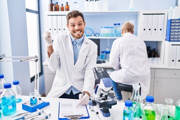 Sticker - Hispanic man and woman working at scientist laboratory screaming proud, celebrating victory and success very excited with raised arm