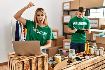 Poster - Young woman and man wearing volunteer t shirt at donations stand annoyed and frustrated shouting with anger, yelling crazy with anger and hand raised