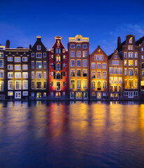 Wall Mural - Damrak, Amsterdam, Netherlands. View of houses during sunset. The famous Dutch canals. A cityscape in the evening. Travel photography.