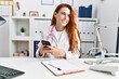 © Krakenimages.com - Young redhead woman wearing doctor uniform using smartphone at hospital