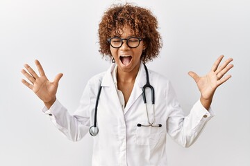 Poster - Young african american woman wearing doctor uniform and stethoscope celebrating mad and crazy for success with arms raised and closed eyes screaming excited. winner concept