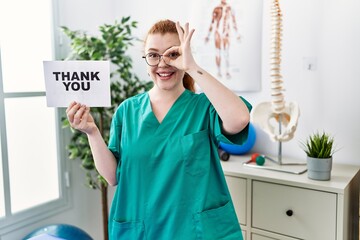 Sticker - Young redhead physiotherapist woman working at pain recovery clinic holding thank you banner smiling happy doing ok sign with hand on eye looking through fingers