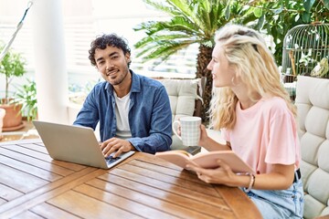 Poster - Young couple smiling happy using laptop and drinking cofffe sitting on the table at terrace.