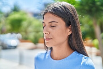 Canvas Print - Young beautiful hispanic woman breathing with closed eyes at park