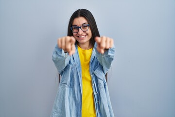 Poster - Young hispanic woman standing over blue background pointing to you and the camera with fingers, smiling positive and cheerful