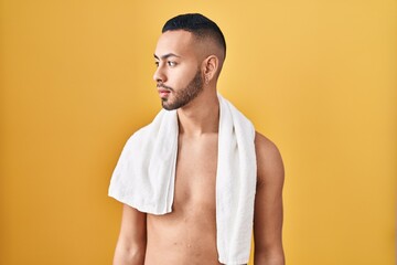 Wall Mural - Young hispanic man standing shirtless with towel looking to side, relax profile pose with natural face and confident smile.