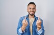 Young hispanic man standing over isolated background showing middle finger doing fuck you bad expression, provocation and rude attitude. screaming excited