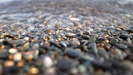 close-up of a pebbly beach and the water surface of a clear calm sea. super slow motion.