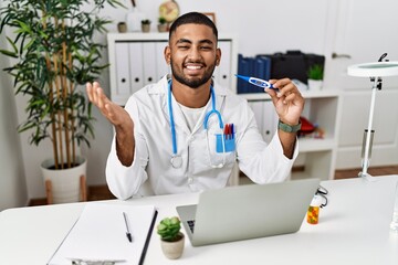 Canvas Print - Young indian doctor holding thermometer celebrating achievement with happy smile and winner expression with raised hand