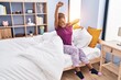 © Krakenimages.com - African american woman waking up stretching arms at bedroom