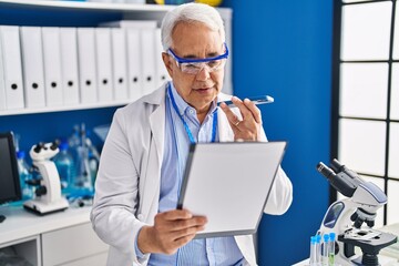 Wall Mural - Senior man scientist talking on the smartphone writing on document at laboratory