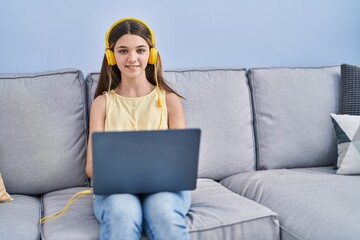 Sticker - Adorable girl using laptop sitting on sofa at home