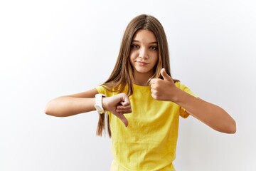 Poster - Young brunette teenager standing together over isolated background doing thumbs up and down, disagreement and agreement expression. crazy conflict