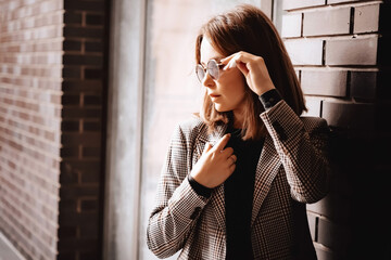 A girl in a business suit in the old town with glasses