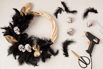 DIY halloween wreath background. Process of making wreath with glue gun, black feathers, skulls and golden leaves