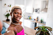Happy black transsexual man taking selfie in modern apartment at kitchen