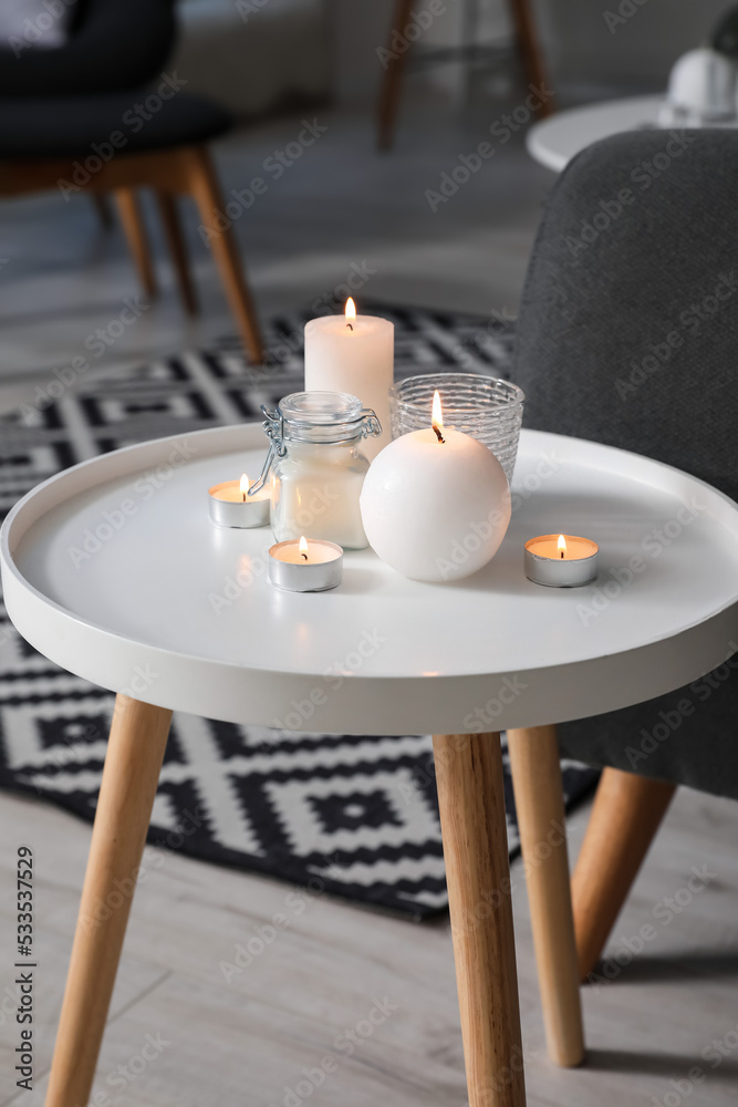 White table with burning candles in living room