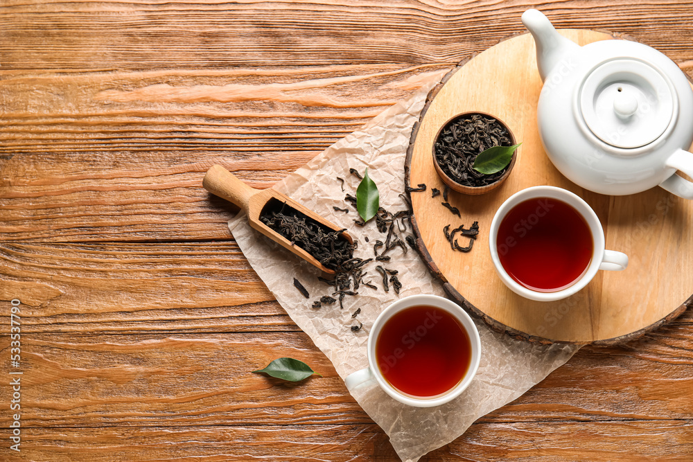Composition with hot black tea on wooden background, top view