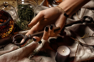 Witch holding metal key on table, closeup