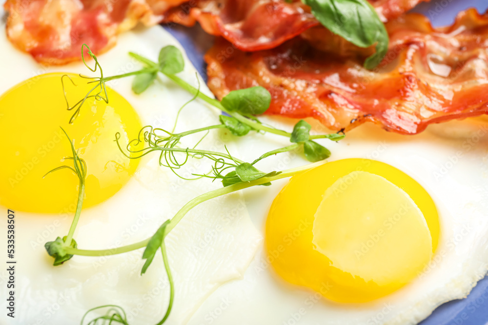 Tasty fried eggs with green sprouts, closeup