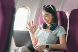 Fototapeta  - Joyful asian woman sits in the airplane and using laptop while go to travel