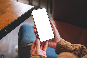 Mockup image of a woman holding mobile phone with blank desktop screen in cafe