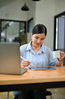 © bongkarn - Attractive millennial Asian businesswoman using digital tablet while sipping her morning office