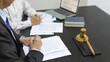 © Puwasit Inyavileart - Lawyers or judges sign documents in accordance with legal and fair terms of agreement, Legal Ethics and Integrity, scales of justice, law hammer, Litigation and legal services.