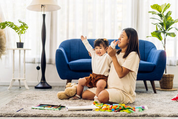 Wall Mural - Portrait of enjoy happy love asian family mother with little asian girl smiling activity learn and skill brain training play with toy build wooden blocks board education game at home