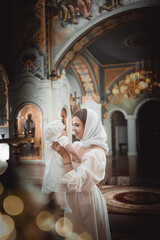 a mother with a small child in a temple or church prays near an icon and candles or came to a divine service in the Russian Orthodox church, the baptism of a baby