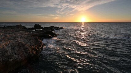 Wall Mural - Amazing video with the sun rising, sea waves and a beautiful rocky coast.