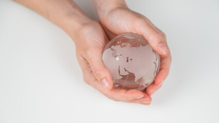 Wall Mural - Crystal globe in female hands on a white background. 