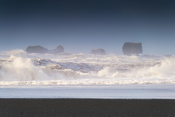 Wall Mural - Reynisfjara, Iceland. A view of a popular spot in Iceland. Rocks during a storm. High waves. Pebbles on the seashore. Popular place to travel.