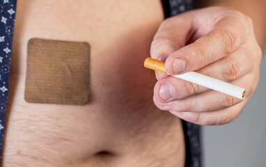 a cigarette is in the man's hand against the background of an anti-smoking patch glued to the human 