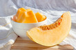 Fresh sweet juicy honey melon (cantaloupe) slices in a white bowl in the kitchen in summer.