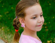 © Александр Логунов - A little beautiful girl in a pink blouse and with a pigtail smiles looking away and on her earlobe is a flower petal instead of an earring